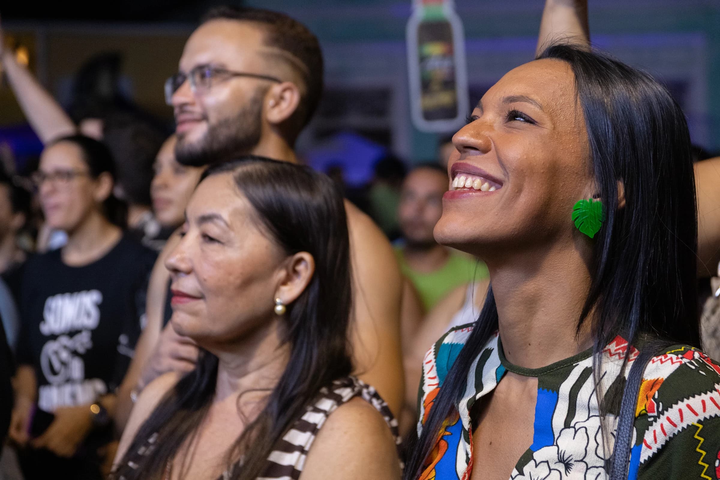 Pessoas na plateia sorriem enquanto acompanham uma apresentação.